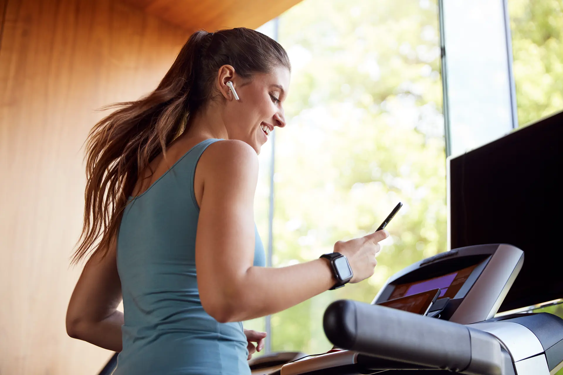 Woman looking at smartphone while running on a treadmill