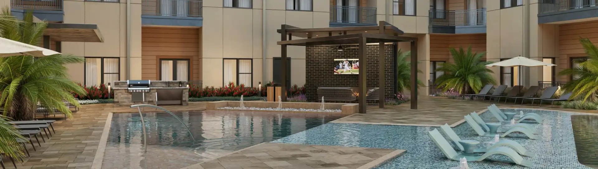 swimming pool with water features, large shallow sun deck with lounge chairs. In the background there is covered lounge seating with a TV next to a built-in gas grill area.