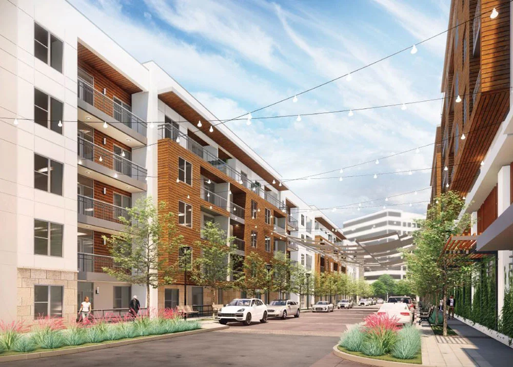 tree lined brick road between buildings with lights strung between them.