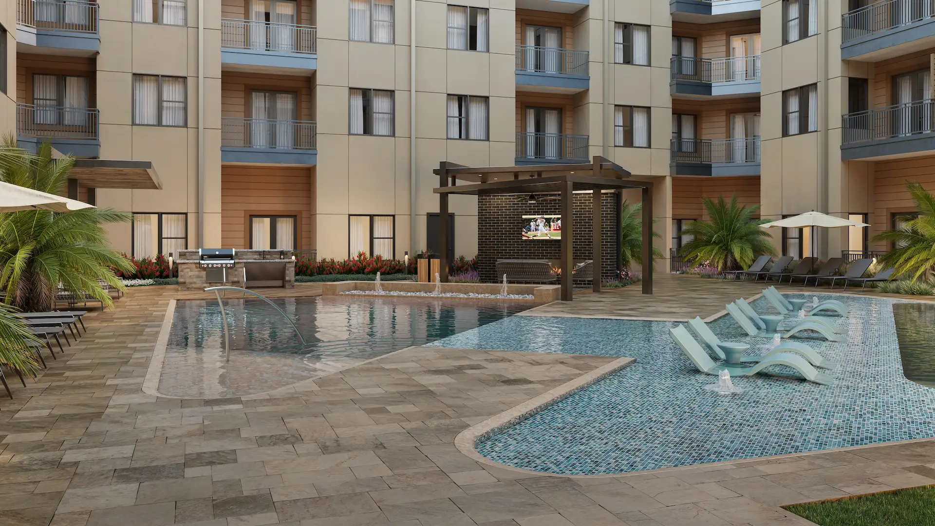 swimming pool with water features, large shallow sun deck with lounge chairs. In the background there is covered lounge seating with a TV next to a built-in gas grill area.